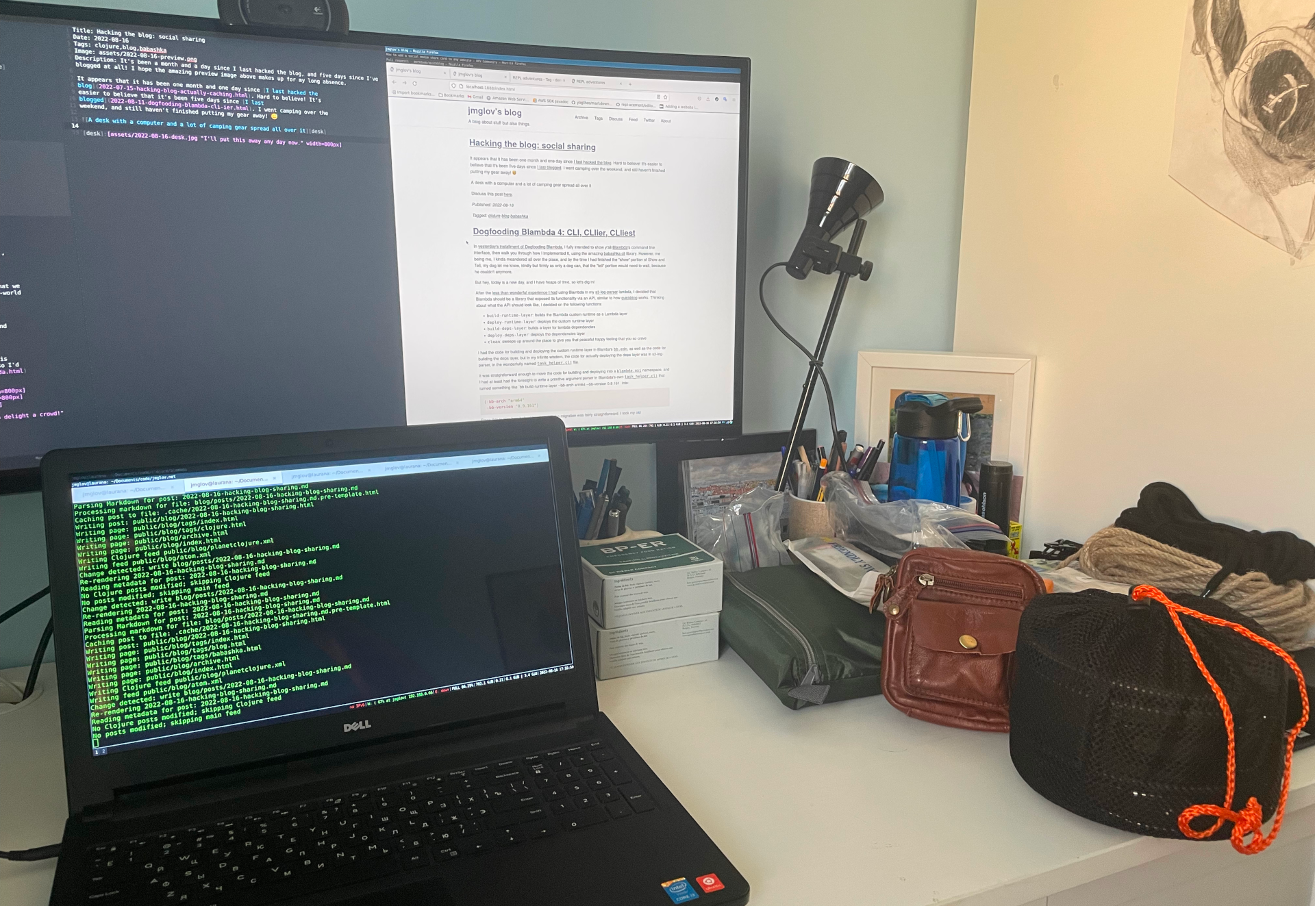 A desk with a computer and a lot of camping gear spread all over it